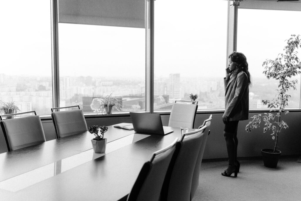 Black and white image of a businesswoman on the phone in a modern office.