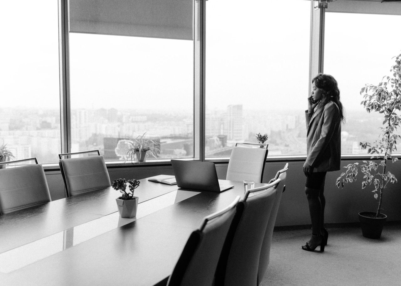 Black and white image of a businesswoman on the phone in a modern office.